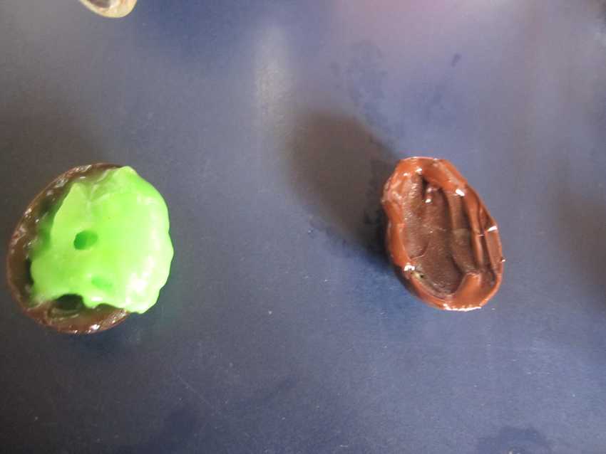 two half chocolate egg shells with green ball in one and fresh chocolate around the rim of the other